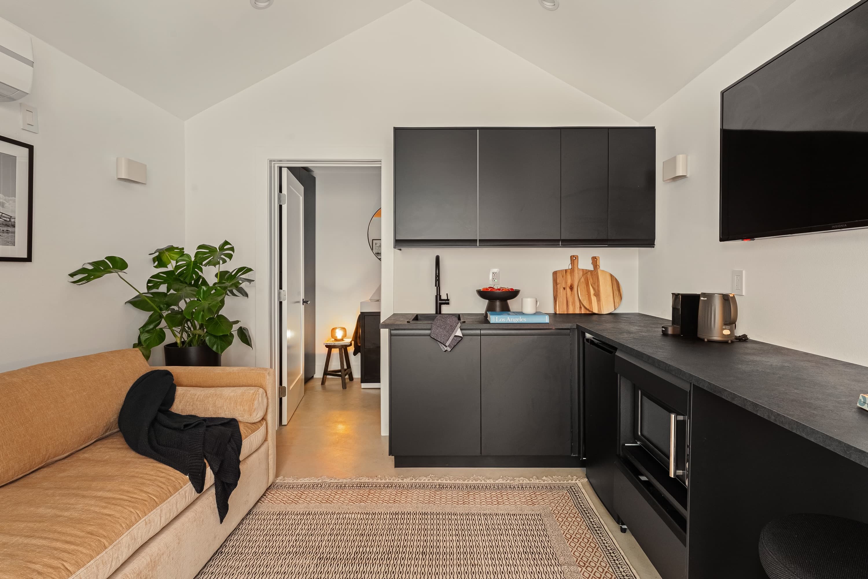 The kitchenette runs along one side. The doorway at the back is the bathroom.